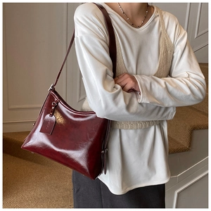 Detail of burgundy leather bucket bag with metallic rivets and adjustable strap