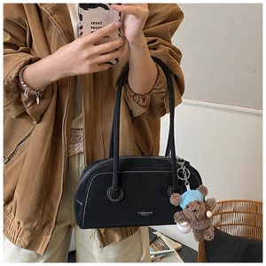 Détail du sac à bandoulière noir mat avec surpiqûres blanches et pendentif ours en peluche