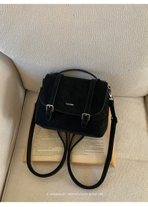 Dettaglio della borsa vintage nera opaca con doppie fibbie su sfondo di libro aperto