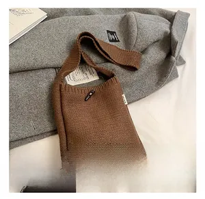 Close-up of brown knit crossbody bag featuring a classic horn button and MISS woven label