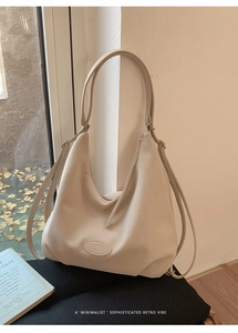 Detail der minimalistischen beigen Ledertasche mit geprägtem ovalem Logo am Boden