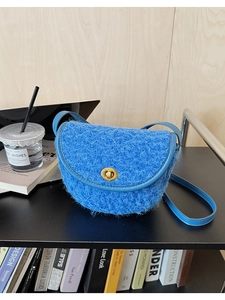 Nahaufnahme der hellblauen Plüsch-Satteltasche mit goldenem Schloss in Wohnszene