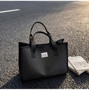 Vue détaillée d'un sac cabas à carreaux noirs avec étiquette tissée au coucher du soleil