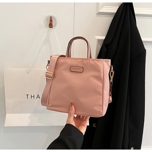 Detailed close-up of pink nylon tote bag featuring golden hardware and CLEAR K logo plate