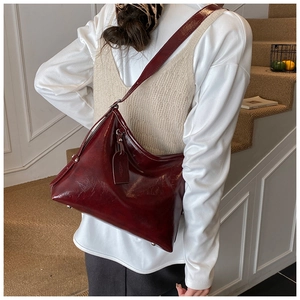 Detail view of the deep red wine tote bag featuring glossy patent leather and side tag