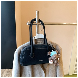 Détail du sac Boston noir avec surpiqûres blanches et pendentif ours en peluche