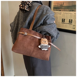 Détail du sac cabas en daim marron foncé avec boucle et pendentif ours en peluche