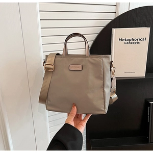 Detail of khaki nylon tote bag with wide strap and metal brand plate by CLEAROK