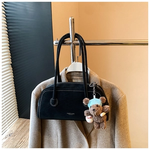 Détail du sac Boston en daim noir avec surpiqûres blanches et charm ours brun