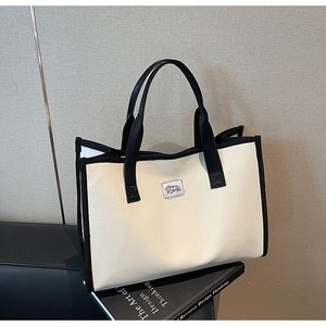 Détail du sac cabas en cuir grainé blanc cassé avec bordure noire et écusson logo
