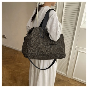 Dettaglio della borsa tote leopardata con manici in pelle nera e tasca esterna a zip
