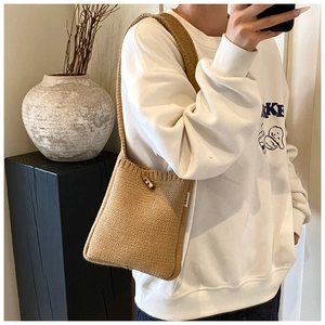 Détail du sac seau en tricot montrant le fermoir corne et la texture tissée