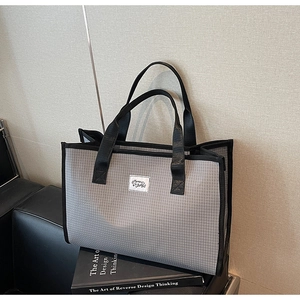 Vue détaillée d'un grand sac cabas à carreaux gris avec anses noires et étiquette tissée