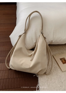 Detail der minimalistischen beigen Kunstledertasche mit ovalem Logo auf Holzboden