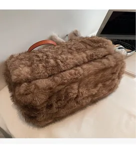Dettaglio della trama in peluche marrone con manico in pelle arancione su questa borsa