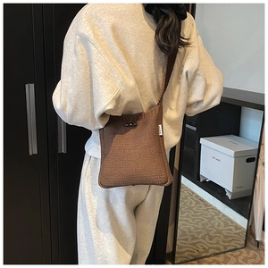 Détail du sac seau en tricot marron foncé avec boucle en corne et bandoulière tissée