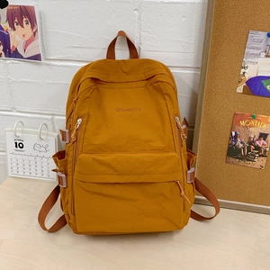 Nahaufnahme des senfgelben Nylon-Rucksacks mit Logostickerei und robusten Reißverschlüssen