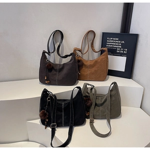 Detail view of four crescent shoulder bags in suede with contrast stitching and fuzzy charms