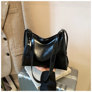 Detail view of large black glossy tote bag with dual straps and smooth wrinkled leather texture