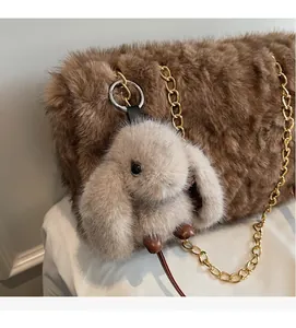 Dettaglio ravvicinato di un portachiavi a coniglio soffice su una borsa in peluche marrone