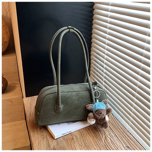Détail du sac Boston en daim vert foncé avec pendentif ours et texture vintage