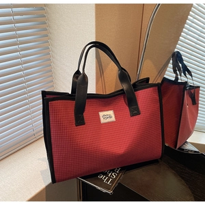 Détail du grand sac cabas à carreaux rouges avec anses en cuir noir et patch de marque