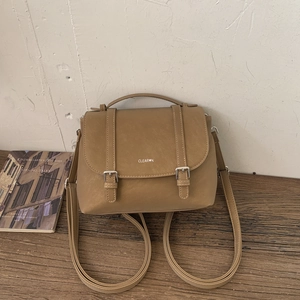 Dettaglio zaino in pelle PU kaki con fibbie metalliche e manico su ripiano in legno