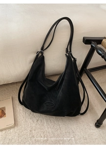 Nahaufnahme der mattschwarzen Ledertasche mit Doppelriemen und ovalem Logo-Patch