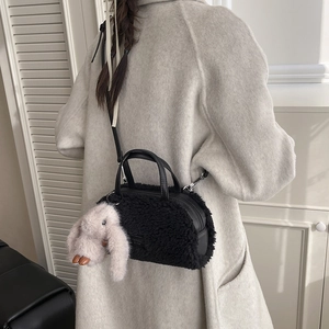 Detail der schwarzen Plüsch-Zylindertasche mit Ledergriffen und niedlichem Hasenanhänger