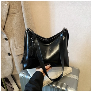 Detail of black patent leather shoulder bag with glossy texture and stylish pleats