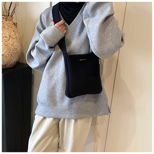 Detail of a black knitted crossbody bag styled with a minimalist Japanese casual outfit