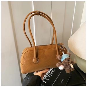 Détail du sac Boston en daim caramel avec charm ours mignon et finitions de qualité