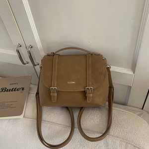 Dettaglio dello zaino vintage in ecopelle marrone con fibbie argentate e logo bianco