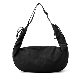 Detail of black nylon crescent bag featuring side ruching and decorative bow accents