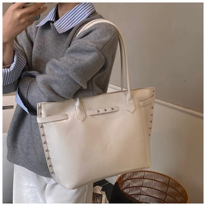 Detail shot of ivory tote bag featuring silver studs and glossy PU leather material