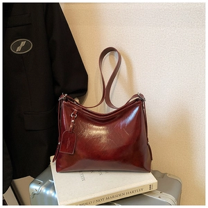 Detail view of burgundy leather bucket bag with metallic studs on a silver suitcase