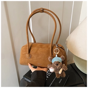 Détail du sac Boston en daim caramel avec un charmant ours en peluche et fines anses
