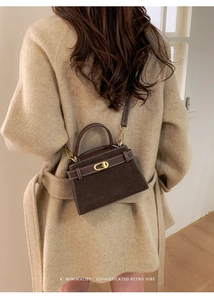 Detail of vintage dark brown suede handbag with golden CD metal clasp on khaki coat
