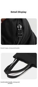 Detail of smooth metal zipper and thick webbing handle on a black large tote bag