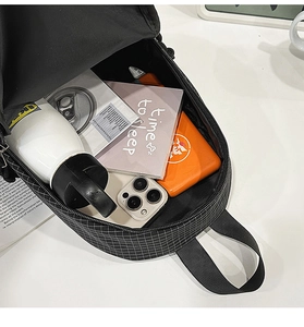 Macro view of checkered sling bag interior showing storage space for laptop and bottle