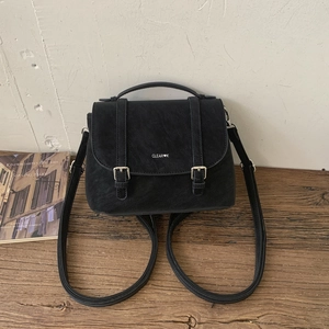 Dettaglio di zaino vintage in pelle nera con fibbie argentate su tavolo in legno