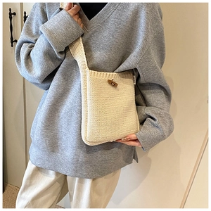 Detail of minimalist cream knit crossbody bag with dark brown wooden horn button