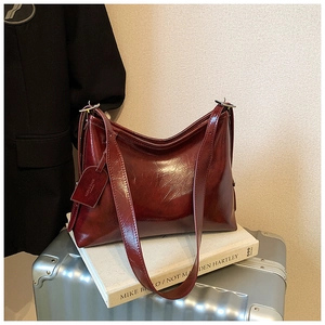 Detail of burgundy oil wax leather shoulder bag with fine texture and glossy finish