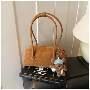 Vue détaillée du sac Boston en daim marron avec un pendentif ours en peluche