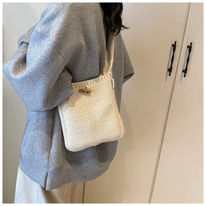 Gros plan détaillé d'un sac seau en tricot beige avec un fermoir à bascule en bois vintage