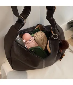 Detail of spacious dark brown hobo bag interior with umbrella, phone, and makeup items