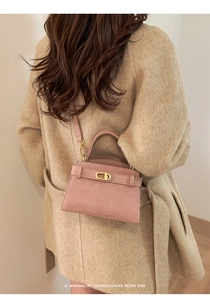 Detail of pink suede handbag with gold clasp closure and removable shoulder strap