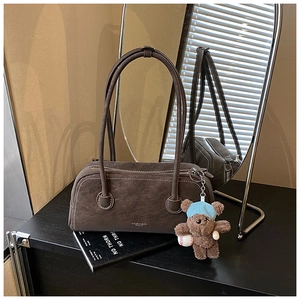 Détail du sac Boston en daim marron foncé avec un charmant pendentif d'ours bleu