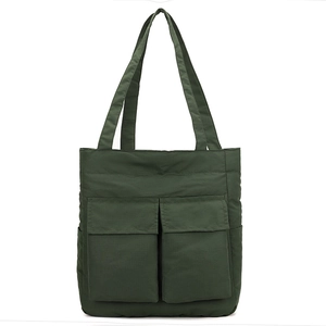 Close-up of deep green nylon tote bag featuring functional front pockets and wide straps