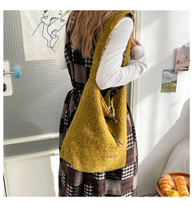 Detail of mustard yellow plush hobo bag with wide shoulder strap and leather patch logo